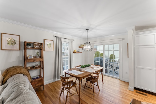 dining room with visible vents, light wood-style flooring, an inviting chandelier, ornamental molding, and baseboards