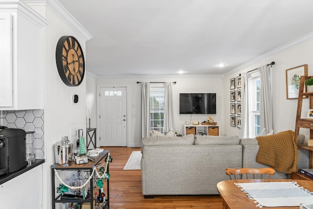 living room featuring plenty of natural light, crown molding, and wood finished floors