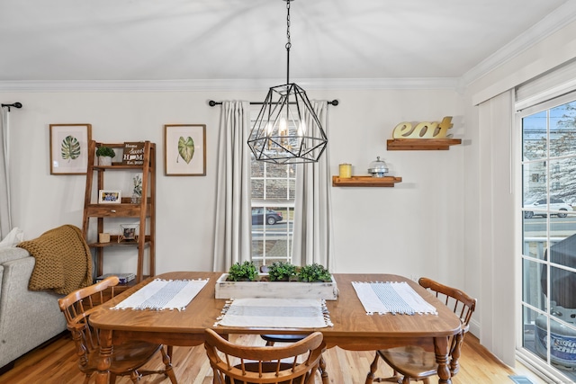 dining area with ornamental molding, a chandelier, and light wood finished floors