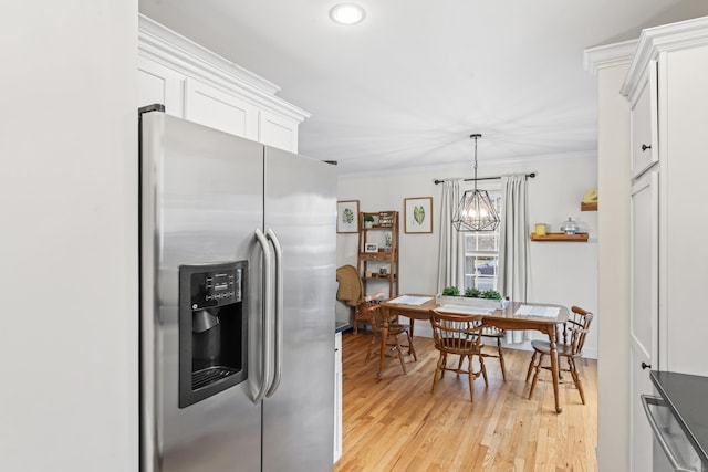 kitchen featuring light wood finished floors, stainless steel fridge with ice dispenser, ornamental molding, hanging light fixtures, and white cabinetry