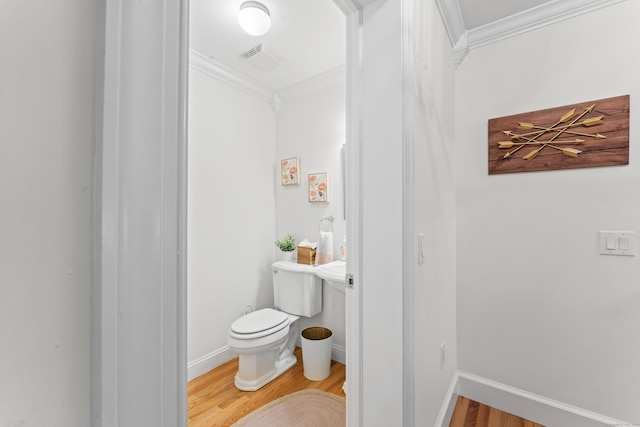 bathroom with toilet, wood finished floors, visible vents, and crown molding