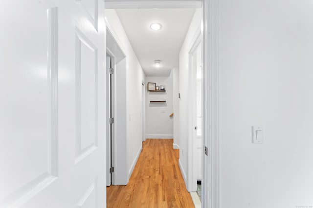 corridor with baseboards and light wood-style floors