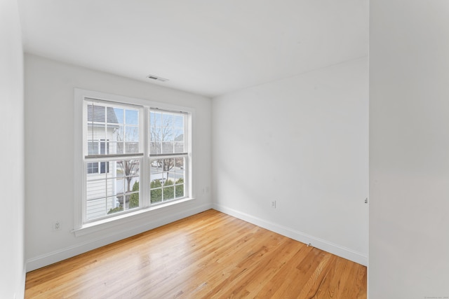 spare room featuring light wood-style floors, visible vents, and baseboards