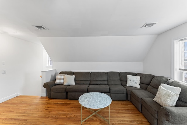 living area featuring lofted ceiling, wood finished floors, visible vents, and baseboards