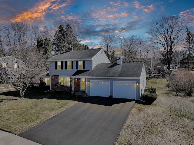 view of front facade featuring aphalt driveway, brick siding, a chimney, a front yard, and a garage