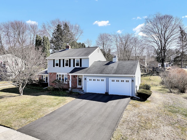 view of front of house with a garage, brick siding, driveway, a chimney, and a front yard