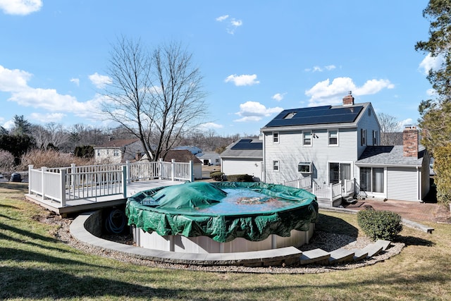 view of pool featuring a lawn, a wooden deck, and a covered pool