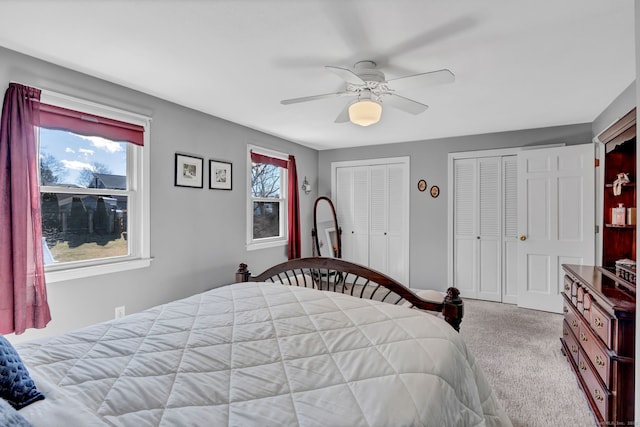 bedroom featuring ceiling fan, carpet floors, and two closets