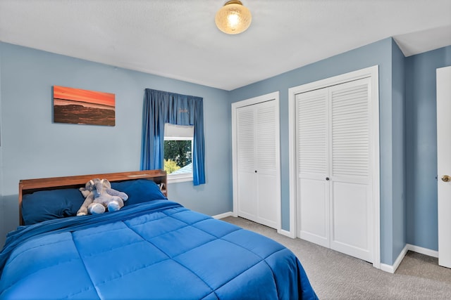 bedroom with baseboards, carpet floors, and multiple closets