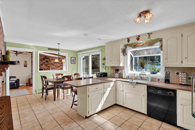 kitchen featuring decorative backsplash, black dishwasher, plenty of natural light, and a sink