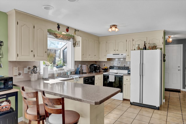 kitchen featuring under cabinet range hood, a peninsula, a sink, decorative backsplash, and black appliances