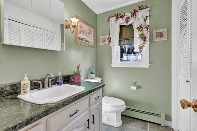 bathroom with a closet, toilet, baseboard heating, vanity, and tile patterned floors