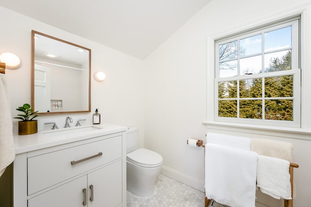 bathroom with toilet, vaulted ceiling, vanity, baseboards, and tile patterned floors