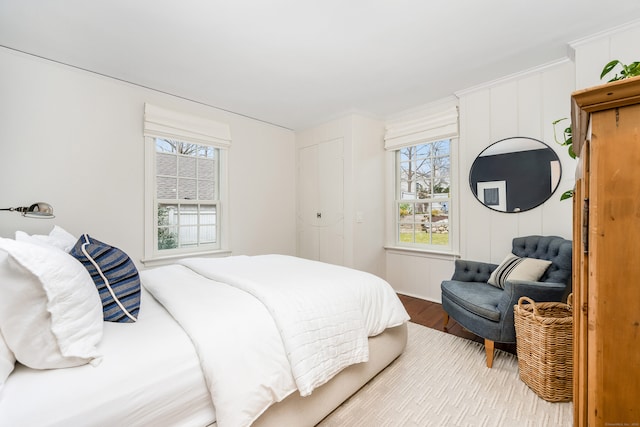 bedroom with ornamental molding and wood finished floors