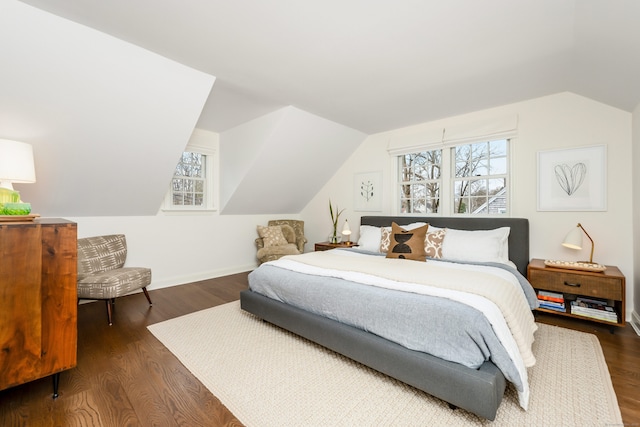 bedroom with lofted ceiling, dark wood finished floors, and baseboards