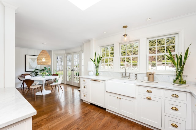 kitchen featuring dark wood-style floors, decorative light fixtures, a sink, and crown molding