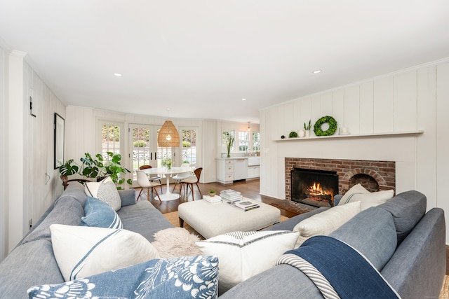 living room with a brick fireplace, a decorative wall, and wood finished floors