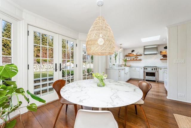 dining space featuring ornamental molding, a skylight, french doors, and wood finished floors