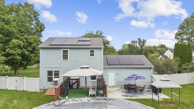 back of property with roof mounted solar panels, a gazebo, a gate, and a yard