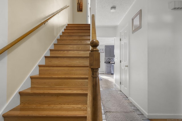 stairway featuring baseboards and a textured ceiling