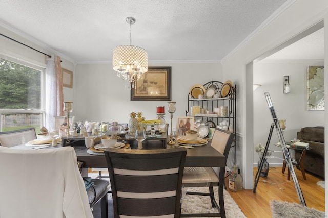 dining space with a chandelier, light wood finished floors, a textured ceiling, and crown molding