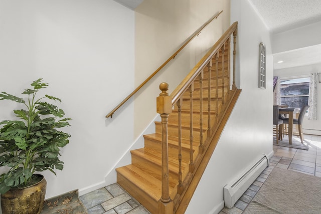 stairway with stone tile flooring, baseboards, a baseboard heating unit, and a textured ceiling