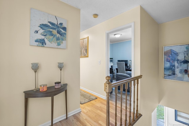 corridor with wood finished floors, an upstairs landing, and baseboards