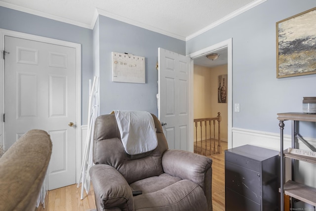 living area featuring a textured ceiling, light wood-style flooring, and crown molding