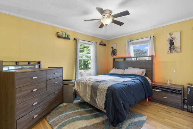 bedroom featuring light wood-type flooring, crown molding, a textured ceiling, and ceiling fan