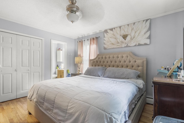 bedroom with ornamental molding, a closet, baseboard heating, and wood finished floors