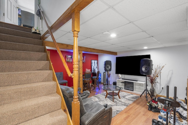 living room featuring a paneled ceiling, wood finished floors, recessed lighting, and stairs