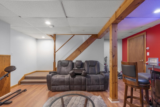 home theater featuring a paneled ceiling, baseboards, and wood finished floors