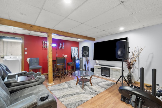 living area with a paneled ceiling, separate washer and dryer, and wood finished floors