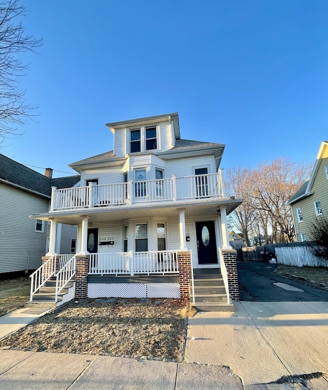 american foursquare style home featuring a balcony and covered porch