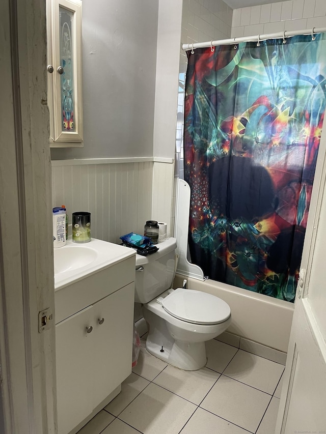 bathroom featuring a wainscoted wall, shower / bath combination with curtain, toilet, vanity, and tile patterned floors