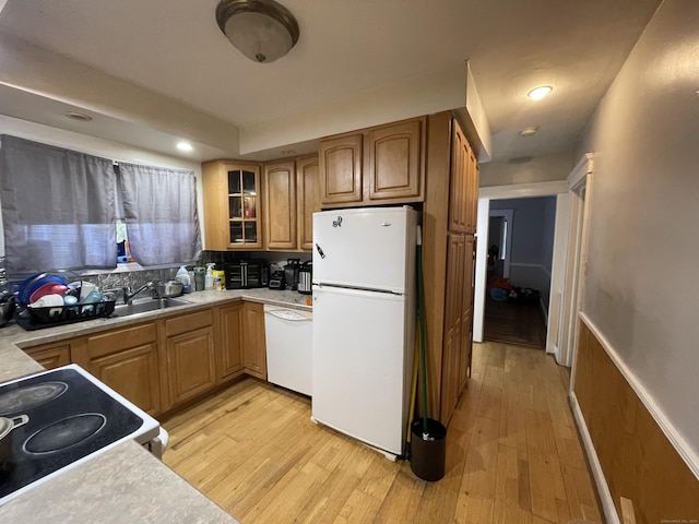 kitchen featuring light wood-type flooring, white appliances, glass insert cabinets, and light countertops