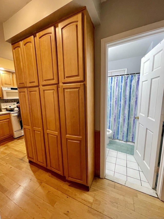 interior space with light wood-type flooring, white appliances, and brown cabinetry