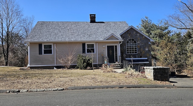 view of front facade with roof with shingles and a chimney