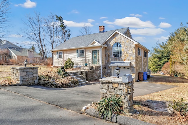 view of front of property featuring a shingled roof, aphalt driveway, a chimney, stone siding, and an attached garage