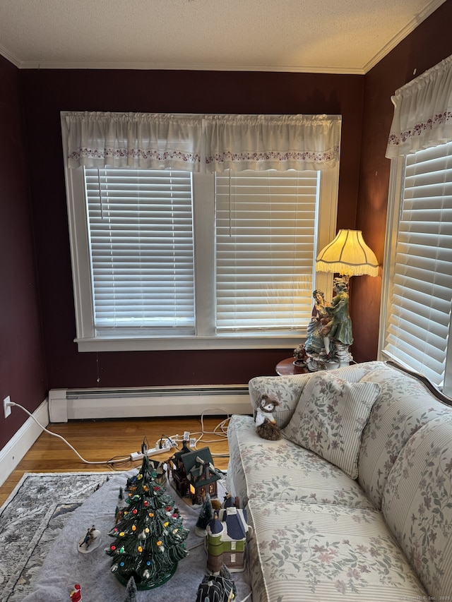 living area featuring baseboards, a textured ceiling, a baseboard heating unit, and wood finished floors