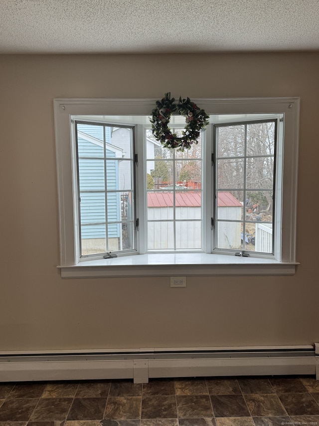 unfurnished dining area with a baseboard heating unit, stone finish flooring, a healthy amount of sunlight, and a textured ceiling