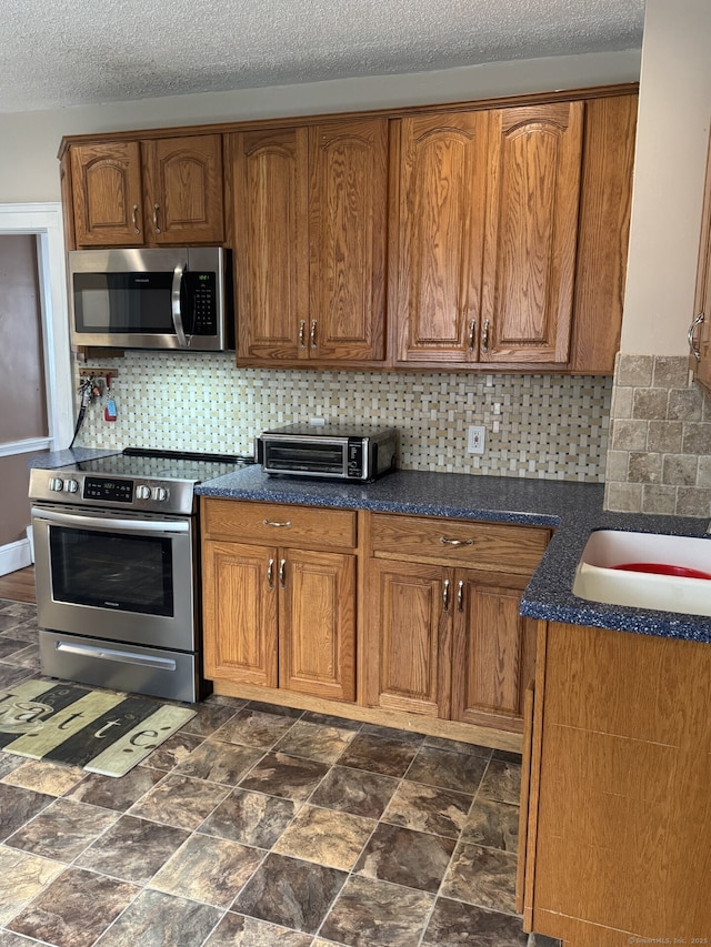 kitchen with stainless steel appliances, a toaster, brown cabinetry, and backsplash