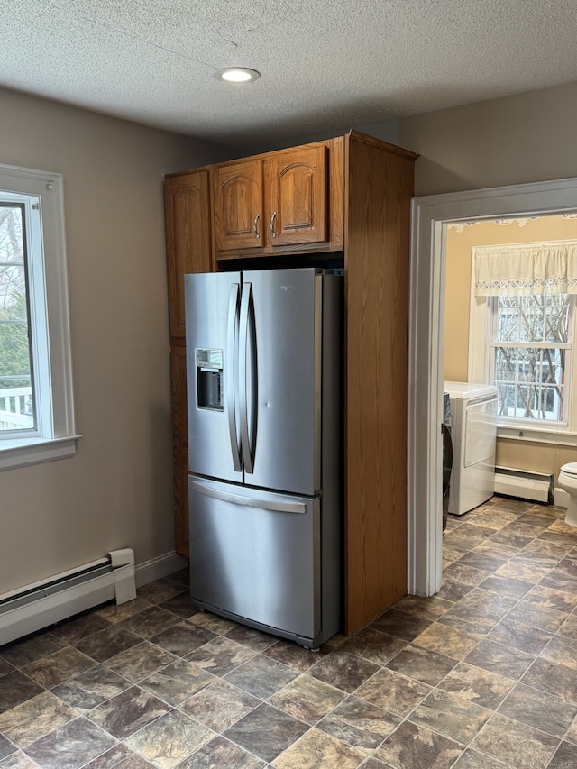 kitchen with a baseboard radiator, baseboard heating, brown cabinetry, stainless steel fridge, and baseboards