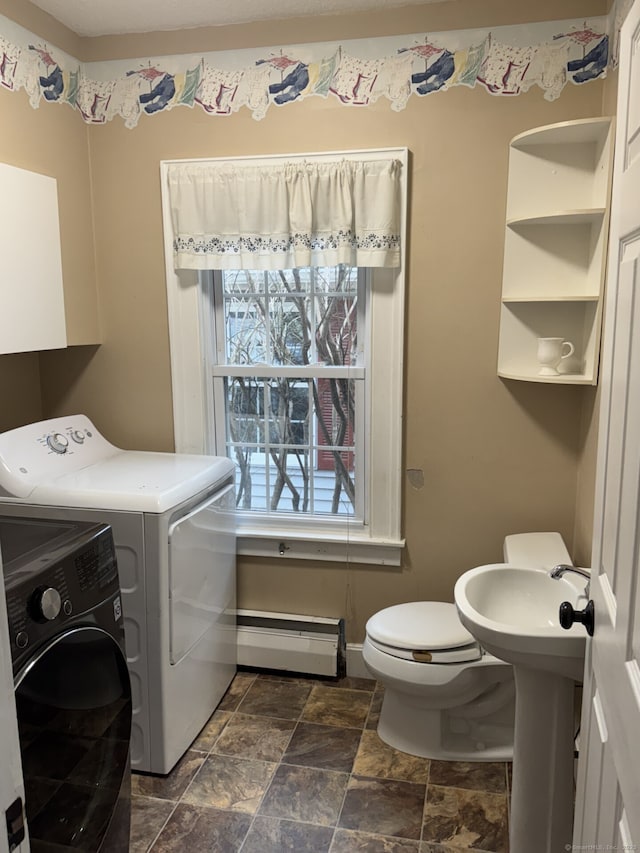 laundry room with laundry area, baseboards, a baseboard radiator, stone finish flooring, and washing machine and dryer