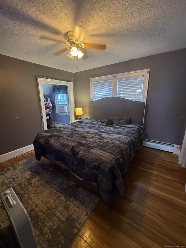 bedroom featuring a baseboard radiator, multiple windows, baseboards, and wood finished floors