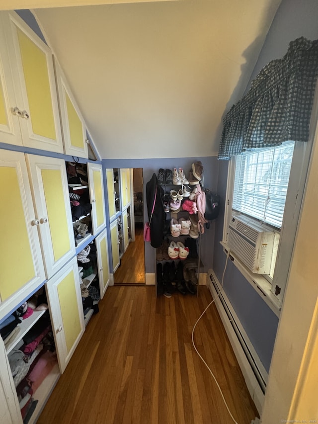 interior space with vaulted ceiling, a baseboard radiator, wood finished floors, and cooling unit