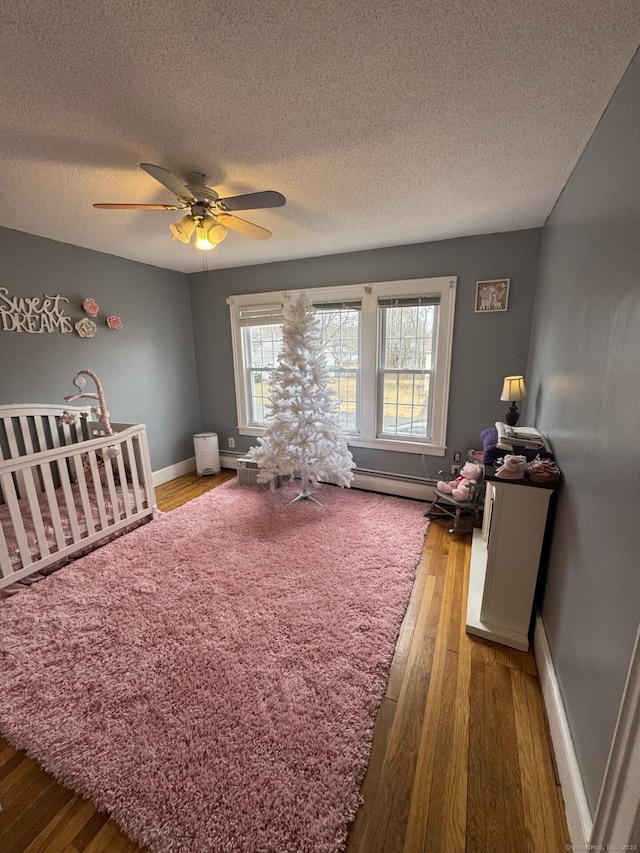 bedroom featuring ceiling fan, multiple windows, wood finished floors, and baseboards