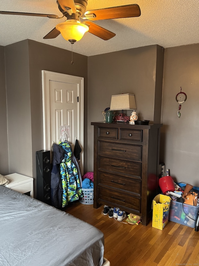 bedroom with a textured ceiling, a ceiling fan, and wood finished floors