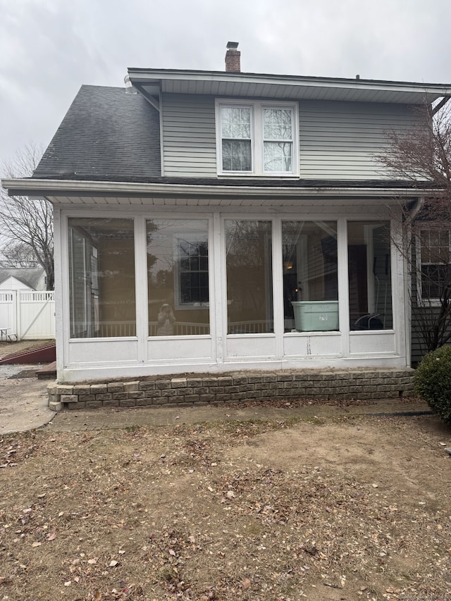 rear view of house featuring a sunroom and a chimney