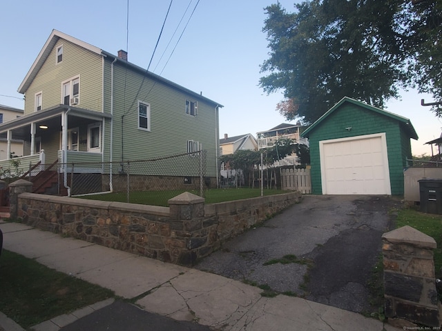 view of home's exterior featuring a detached garage, an outbuilding, driveway, and fence